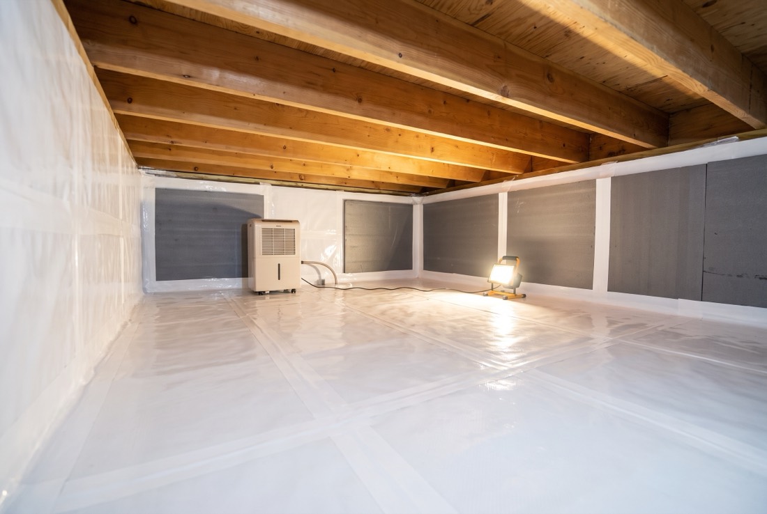 A finished encapsulated crawl space with sealed liner, taped seams and a dehumidifier running in the corner